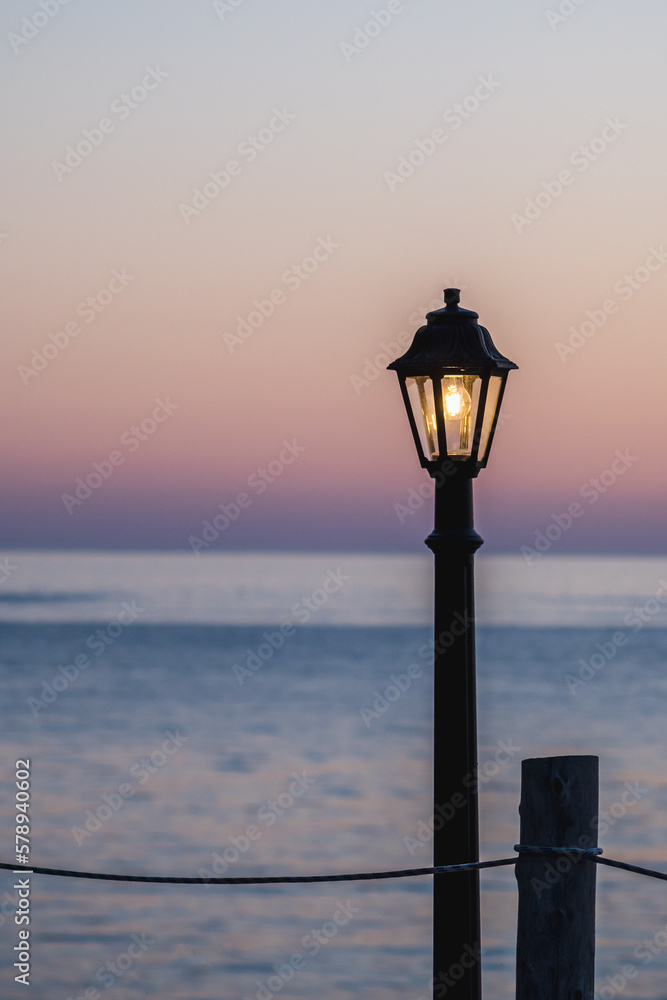 A vintage street lantern shines on the beach