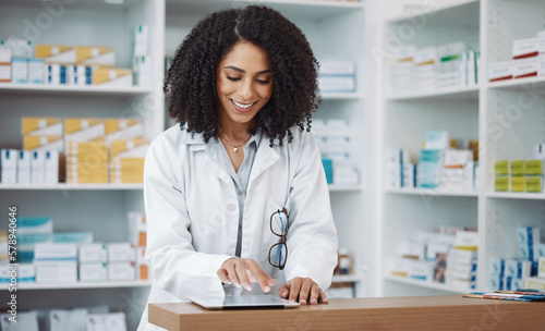 Pharmacy, medical and pharmacist typing on a tablet searching medicine online, internet and web in a dispensary. Black woman, drugs and healthcare professional in a drugstore for health products