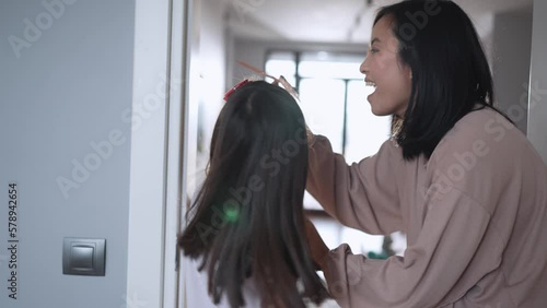 Happy Asian mom measures her daughter's height at home