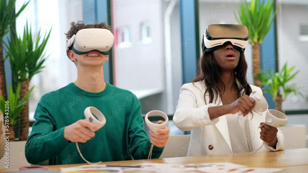 Business conference in VR in an office. Multiracial group of people talking and using VR glasses and controllers, papers on the table Business conference in VR in an office. Multiracial group of people talking and using VR glasses and controllers, papers on the table