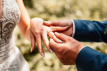 Wedding engagement rings. Married couple exchange wedding rings at a wedding ceremony. Groom put a ring on finger his wife.