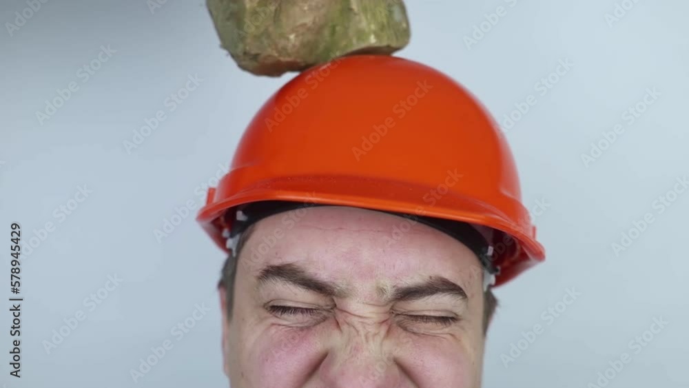 Safety helmet. Brick and a board fall on builder head. Saving a life due to wearing a protective construction helmet. Protection of worker from accidents. Falling objects from a height. Slow mo effect Safety helmet. Brick and a board fall on builder head. Saving a life due to wearing a protective construction helmet. Protection of worker from accidents. Falling objects from a height. Slow mo effect