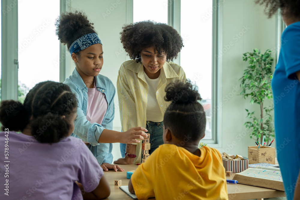 Fototapeta premium Young African American children sitting at school desk and working at their desks in class at the elementary school.