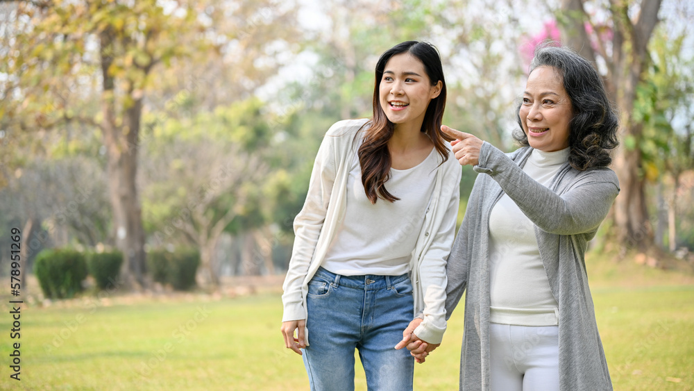 Happy Asian grandmother enjoys talking with her lovely grandchild while strolling in the park Happy Asian grandmother enjoys talking with her lovely grandchild while strolling in the park