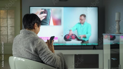 A middle-aged housewife shopping in a TV shop. A professional salesperson convinces a customer to buy a new, unique electric massager. Network advertising, TV shop, telemarketing, online sales. photo
