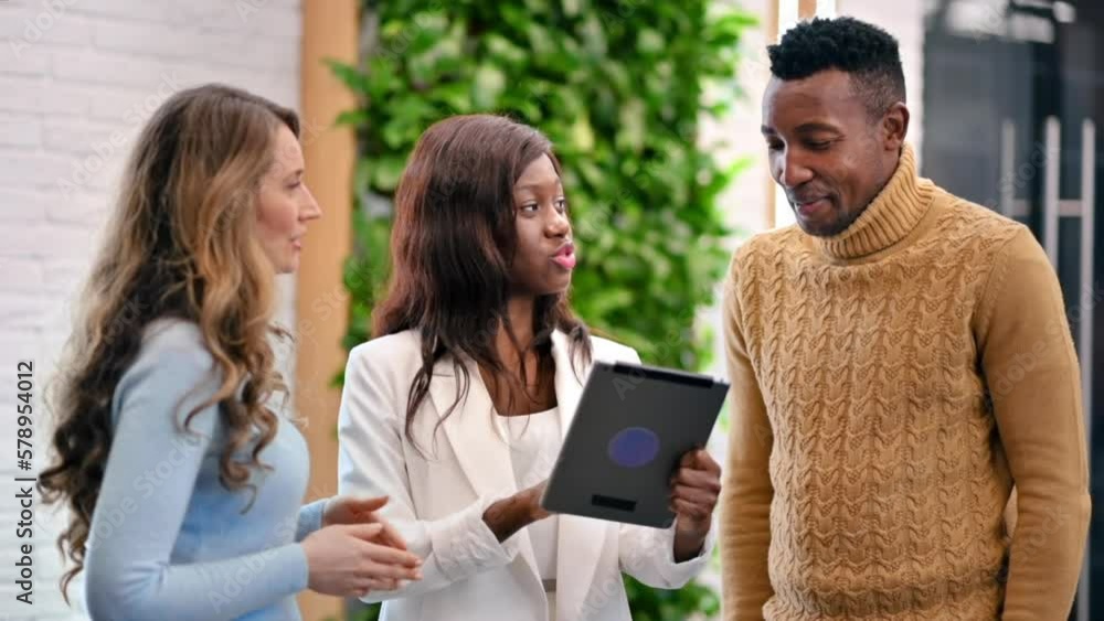 Multiracial group of workers in an office discussing business affairs using a tablet. Slow motion Multiracial group of workers in an office discussing business affairs using a tablet. Slow motion