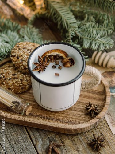 Candle with a wooden wick in an enameled mug on wooden tray. Natural. Christmas candle. Candle with decor. Soft focus