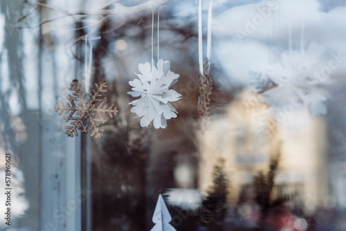 snowflake in window of shop with sunlight & lights in winter christmas photo