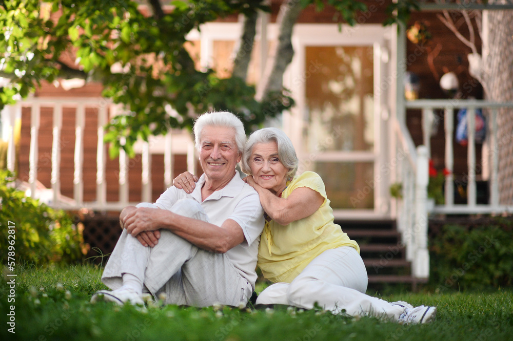 Elderly couple sits on the grass in summer