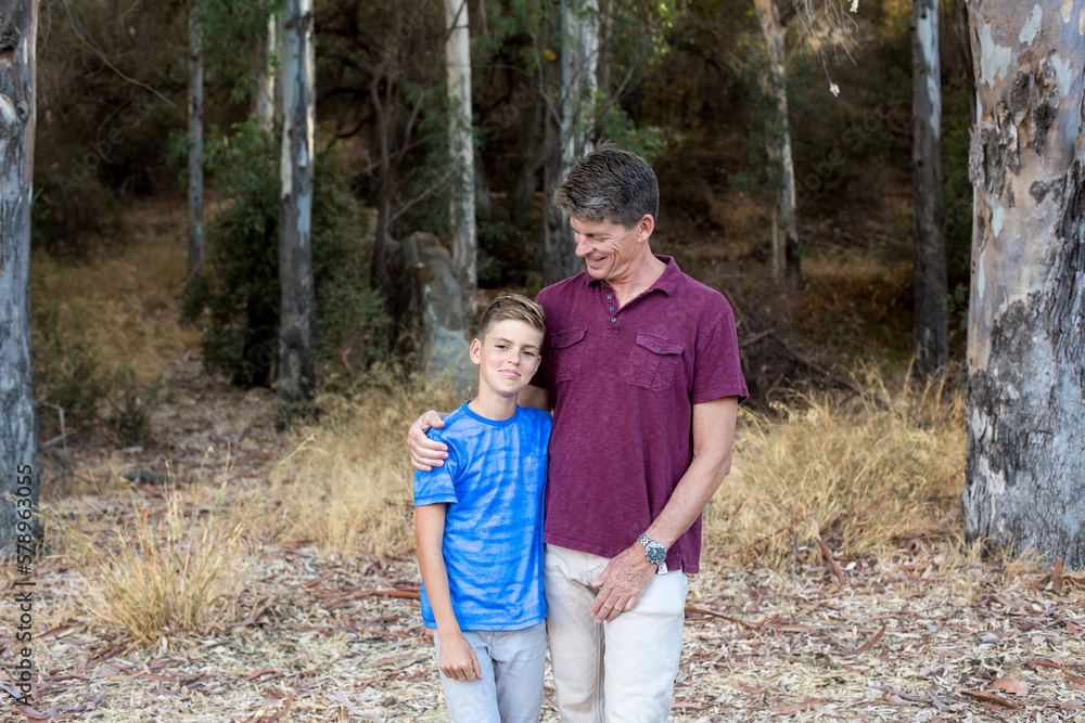Father with arm around son looks down and smiles at him Father with arm around son looks down and smiles at him