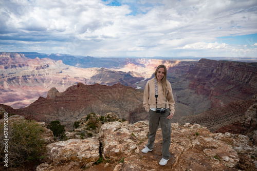 Portrait of a smiling young blonde girl with a vintage photo camera on the precipice of the Grand Canyon