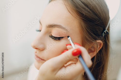Fototapeta Naklejka Na Ścianę i Meble -  Beautiful young woman applying makeup beauty visage brush.