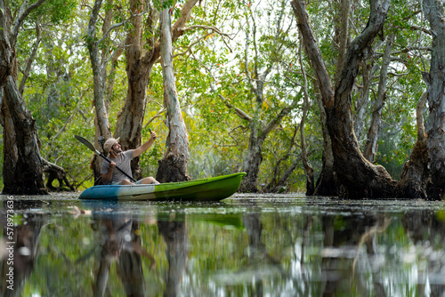 Tablou pe pânză Caucasian man using mobile phone taking selfie during kayaking at mangrove forest on summer vacation