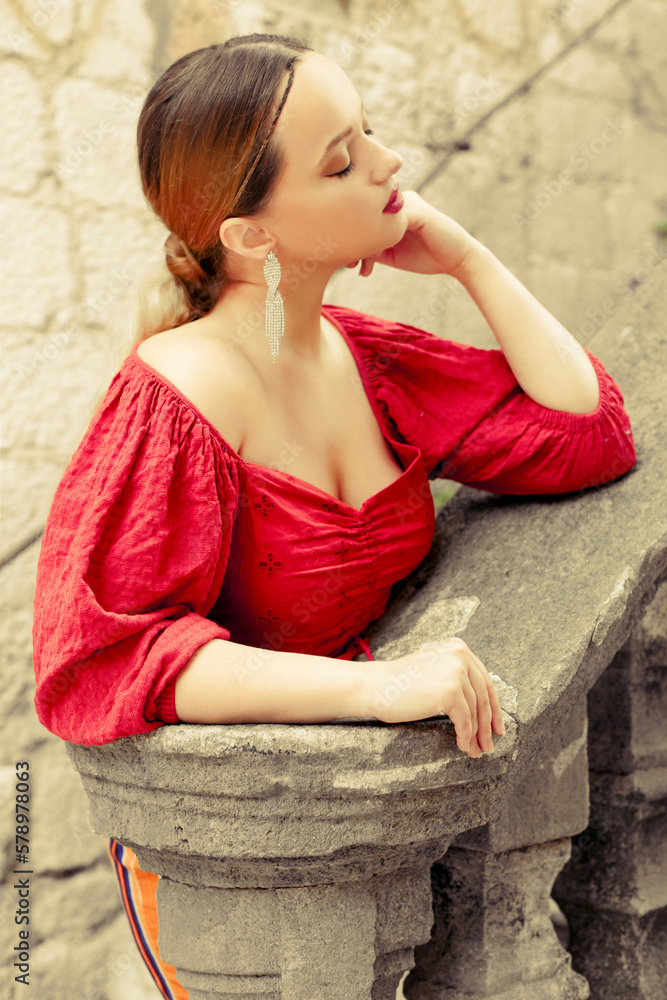 Gorgeous portrait of a beautiful woman in the old city on the stairs. Girl with makeup and hairstyle, long silver earrings posing