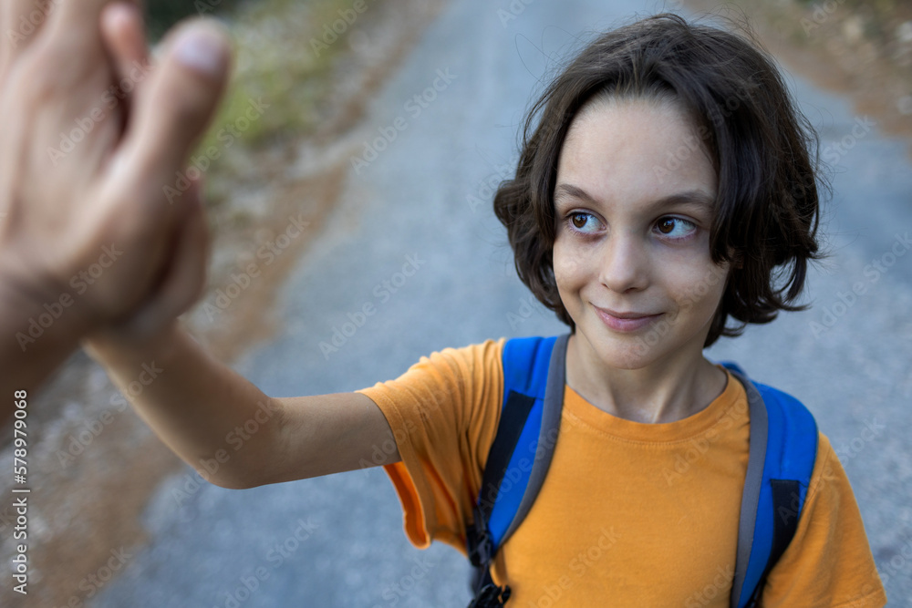 Naklejka premium boy with a backpack gives five. The child enjoys spending time with their parents.
