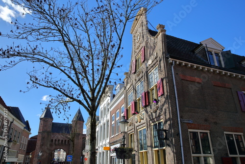 Historic buildings located along the commercial Kamp street in Amersfoort, Utrecht, Netherlands, with Kamperbinnenpoort gate (the historic Eastern acces gate to the city center) in the background photo