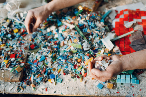 Man mosaics master chooses select smalt glass pieces for mosaic panel. Male mosaicist at work