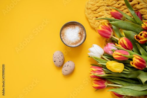 beautiful Easter frame mockup with tulips, eggs and a cup of coffee on a bright yellow background. top view. copy space. flat lay