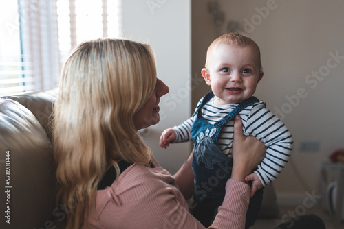 Happy mother and baby boy on the sofa at home