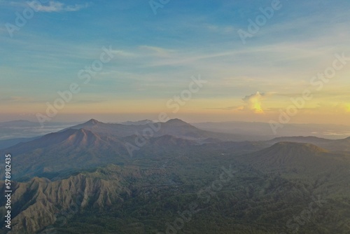 Epic view from the top of Mount Inerie on Flores, overlooking a mountainous landscape with an atmospheric sunrise sky.