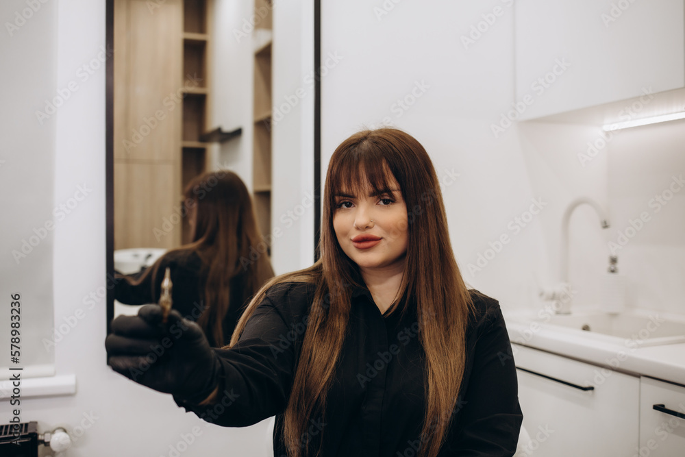 the hands of a permanent makeup artist in black sterile gloves holds a tape in his hands to protect the tattoo machine and wraps it around the hands of a permanent makeup artist in black sterile gloves holds a tape in his hands to protect the tattoo machine and wraps it around