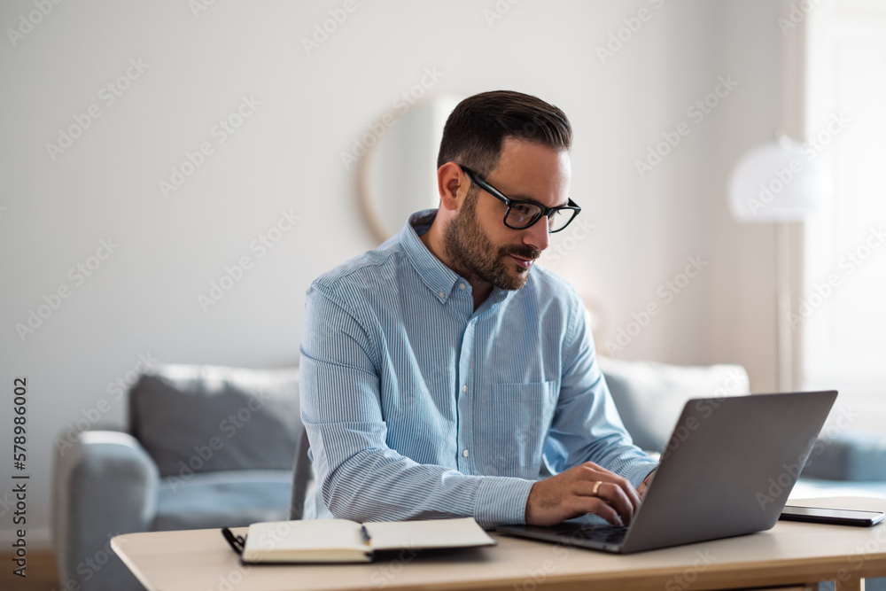 Focused businessman typing on a laptop, sitting at the home office. Focused businessman typing on a laptop, sitting at the home office.