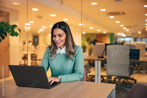 Cheerful woman having an online meeting with colleagues, over the laptop, indoors.