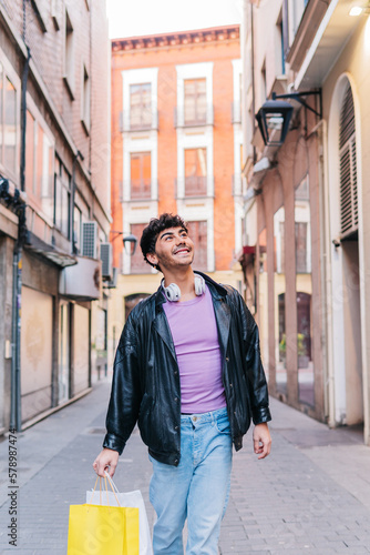 Happy young LGBT person walking on street with shopping bags