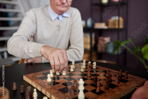 Close up of unrecognizable senior man playing chess in retirement home, copy space
