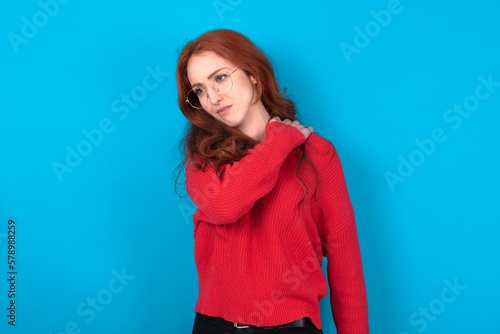 young woman wearing red sweater over blue background got back pain