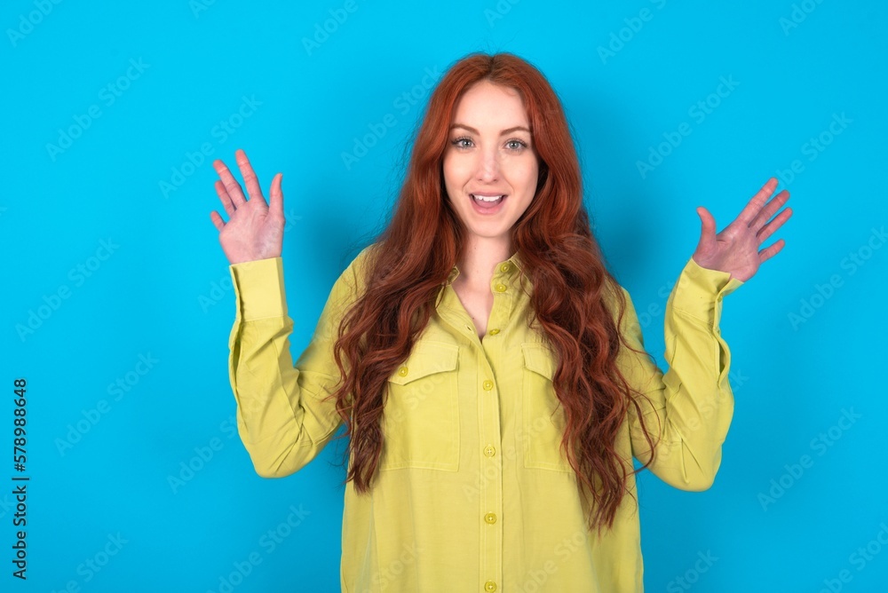 Optimistic young woman wearing green sweater over blue background raises palms from joy, happy to receive awesome present from someone, shouts loudly, Optimistic young woman wearing green sweater over blue background raises palms from joy, happy to receive awesome present from someone, shouts loudly,