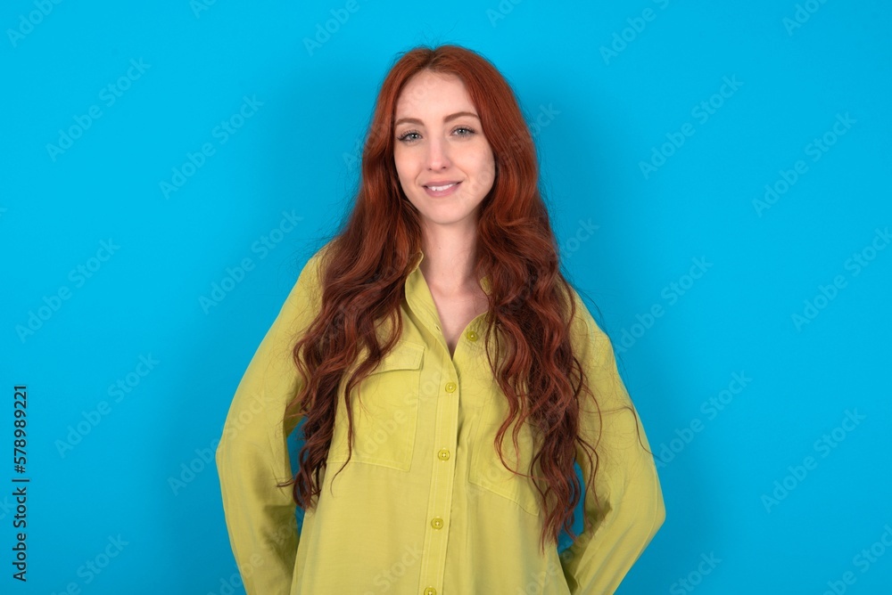 young woman wearing green sweater over blue background with a happy and cool smile on face. Lucky person. young woman wearing green sweater over blue background with a happy and cool smile on face. Lucky person.