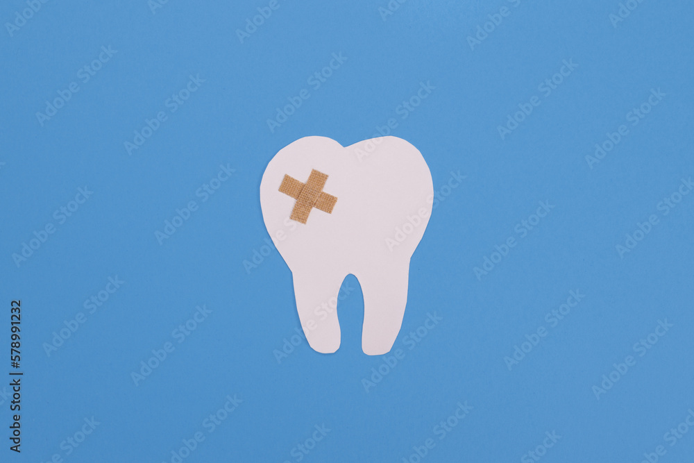 sealed white paper tooth sealed by a shepherd on a blue background. Dental treatment, dentist services concept sealed white paper tooth sealed by a shepherd on a blue background. Dental treatment, dentist services concept