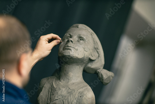 Man sculptor creates sculpt bust clay human woman sculpture. Statue craft creation workshop.