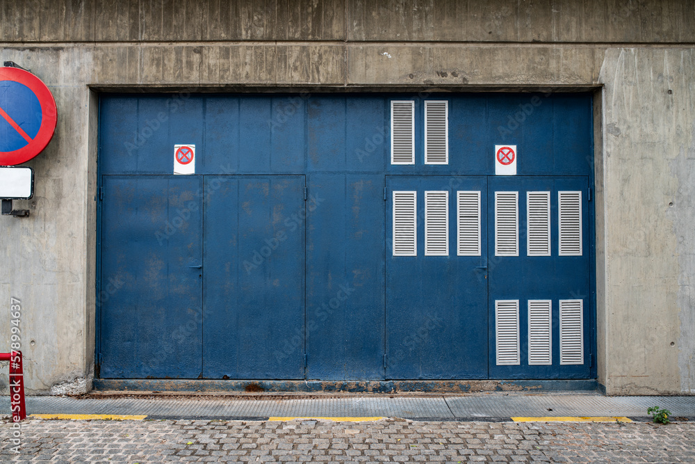Naklejka premium Urban street with blue gates and concrete wall