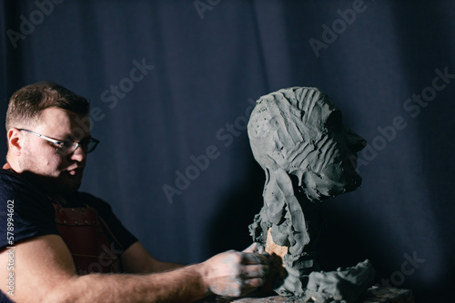 Man sculptor creates sculpt bust clay human woman sculpture. Statue craft creation workshop.