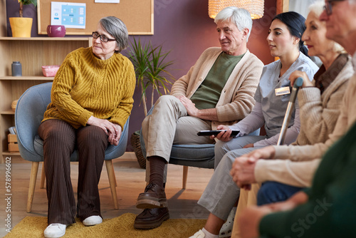 Full length view at group of elderly people watching TV in retirement home together