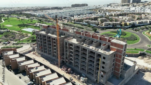 aerial view of a building under construction with green gardens in the background and working machinery photo