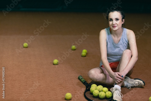 Tennis woman player relaxing with racket and many balls at court. © primipil