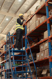Warehouse workers in a large warehouse Climb the ladder to inspect the goods on the top shelves.