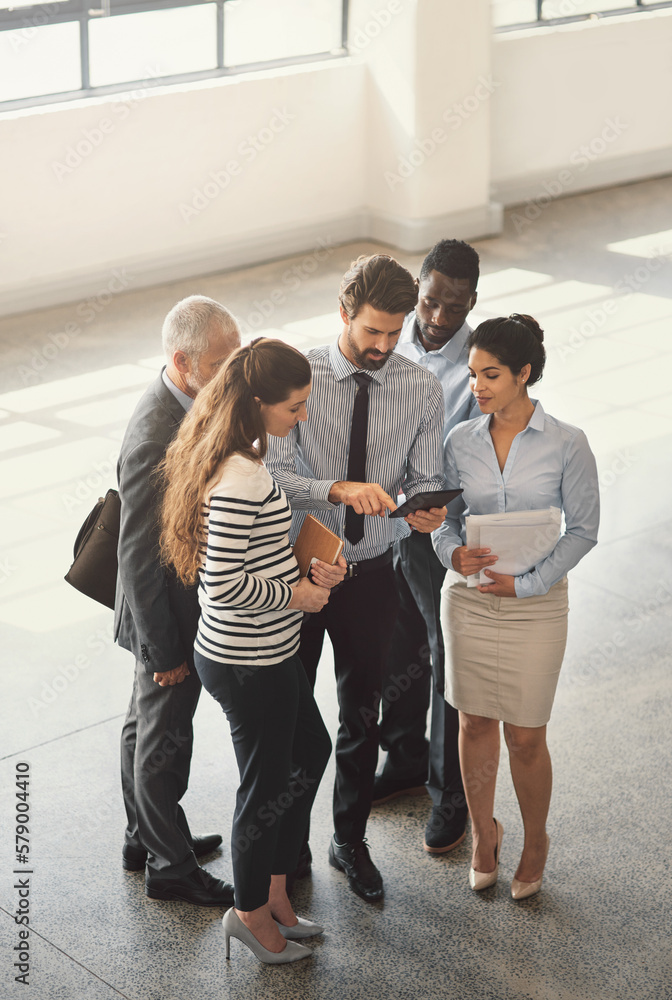 Fototapeta premium Running his plan by the team. High angle shot of a group of businesspeople talking together while standing in an office lobby.