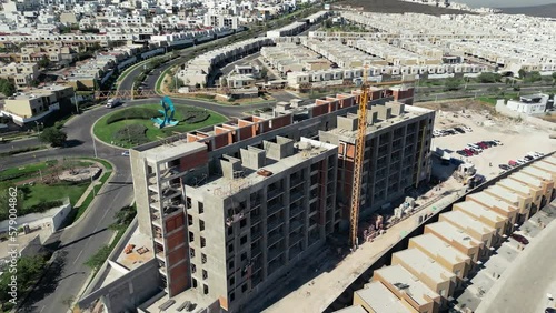 aerial view of a building under construction with green gardens in the background and working machinery photo