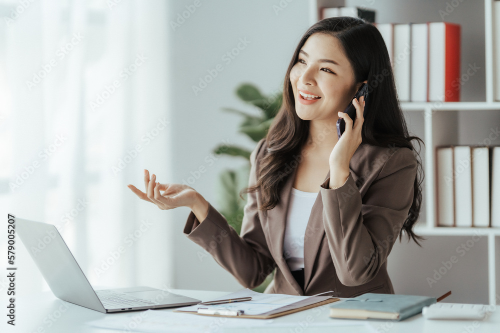 Asian businesswoman in formal suit in office happy and cheerful during using smartphone and working Asian businesswoman in formal suit in office happy and cheerful during using smartphone and working