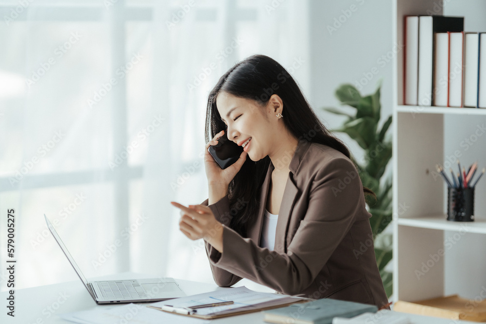 Asian businesswoman in formal suit in office happy and cheerful during using smartphone and working Asian businesswoman in formal suit in office happy and cheerful during using smartphone and working