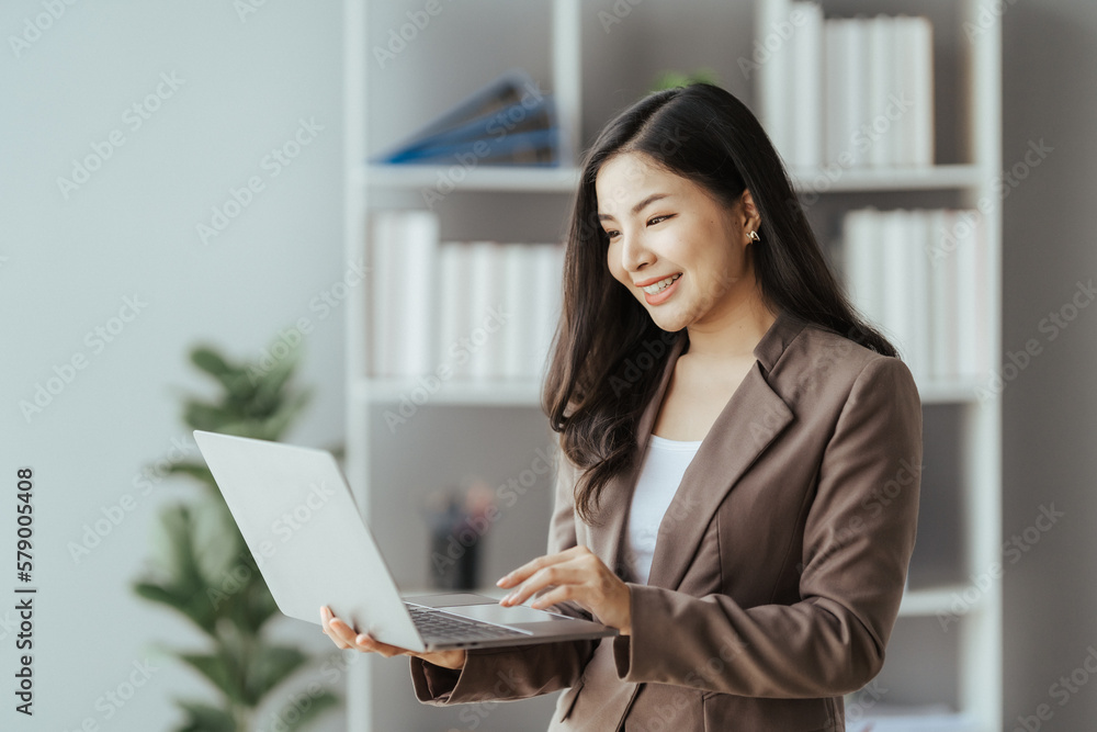 Asian businesswoman in formal suit in office happy and cheerful during using smartphone and working Asian businesswoman in formal suit in office happy and cheerful during using smartphone and working