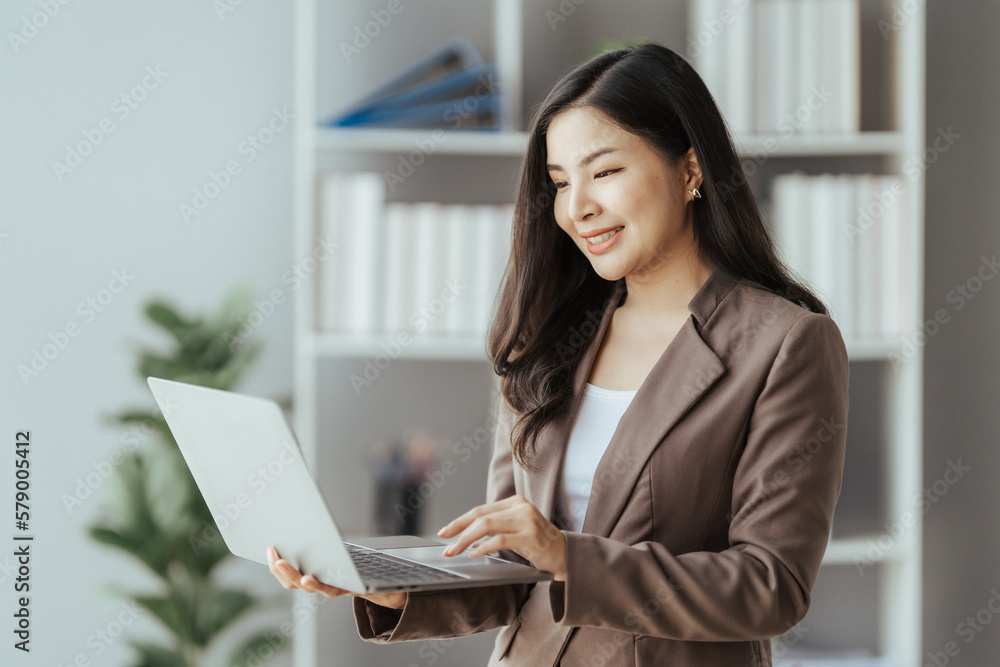 Asian businesswoman in formal suit in office happy and cheerful during using smartphone and working Asian businesswoman in formal suit in office happy and cheerful during using smartphone and working