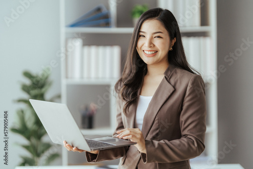 Asian businesswoman in formal suit in office happy and cheerful during using smartphone and working © Kritdanai