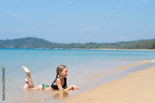 girl lies on the beach with sea waves 