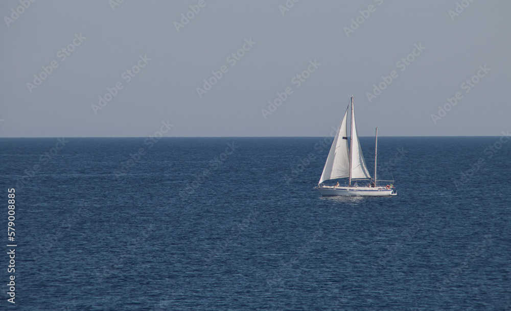 Velero navegando en el horizonte en Gallipoli, Italia. Yate con las velas desplegadas navengando en las aguas turquesas del mar Jónico.