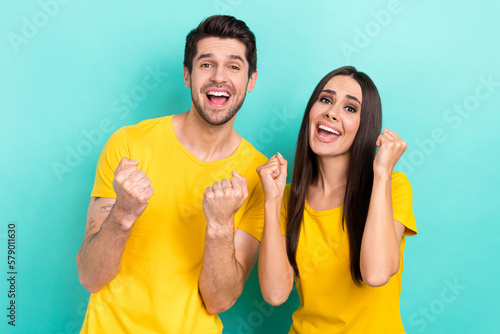 Photo of overjoyed positive optimistic attractive couple fists up hooray celebrate champions final winners isolated on aquamarine color background